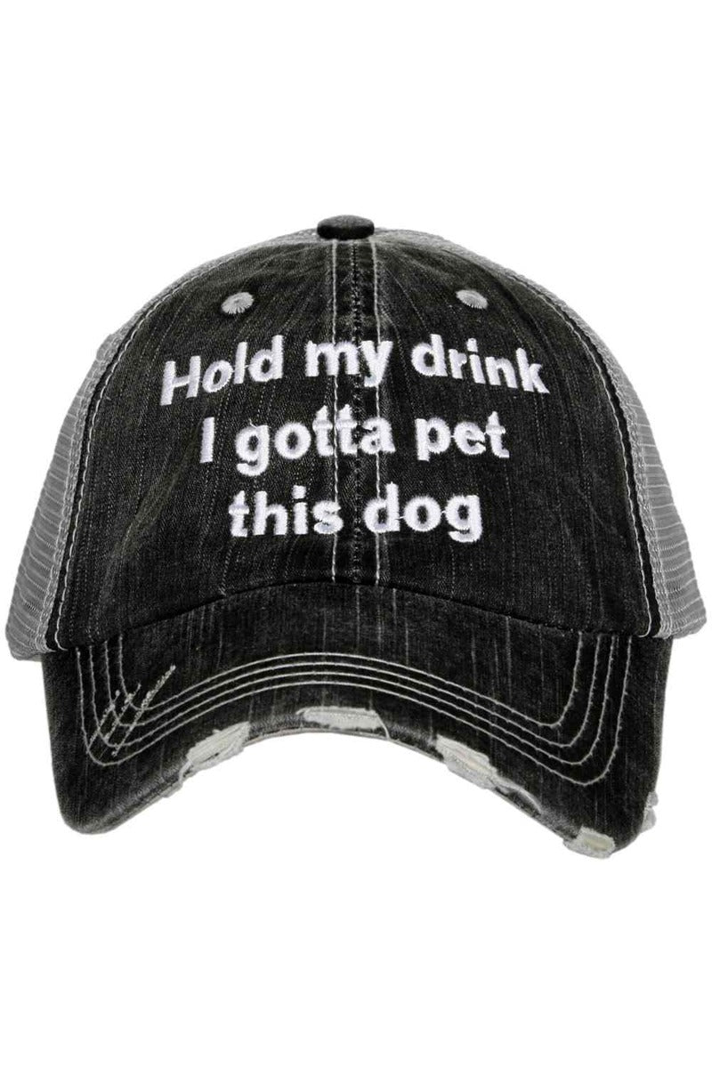 A black and white distressed trucker hat with the words hold my drink i got a pet this dog