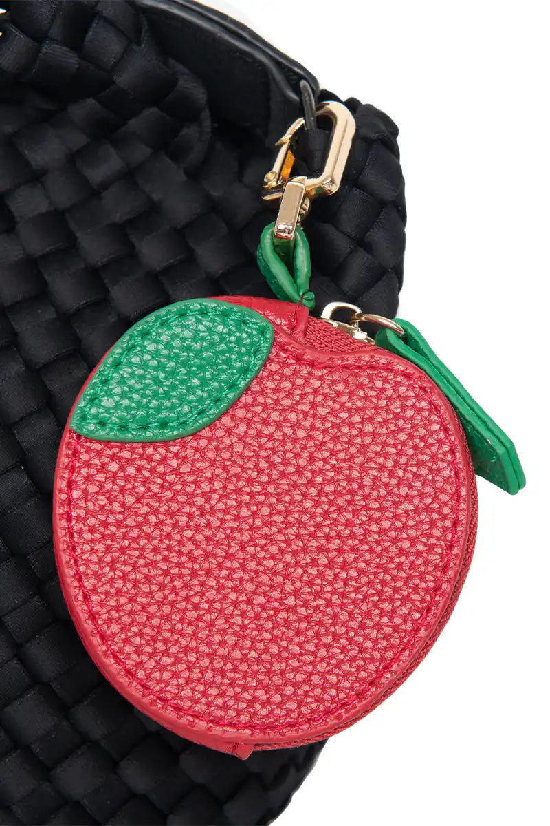 The Katydid Red Apple Coin Zipper Purse, a small round vegan leather accessory with green leaf detail, attaches to your bag with a gold clasp—perfect as a stylish keychain or cute accent for any black woven bag.