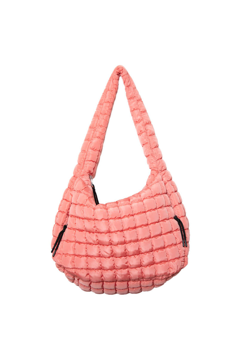 The Katydid Coral Oversized Quilted Hobo Tote Bag features a pink, puffy quilted design with two side zippers and a zipper closure, shown against a plain white background.