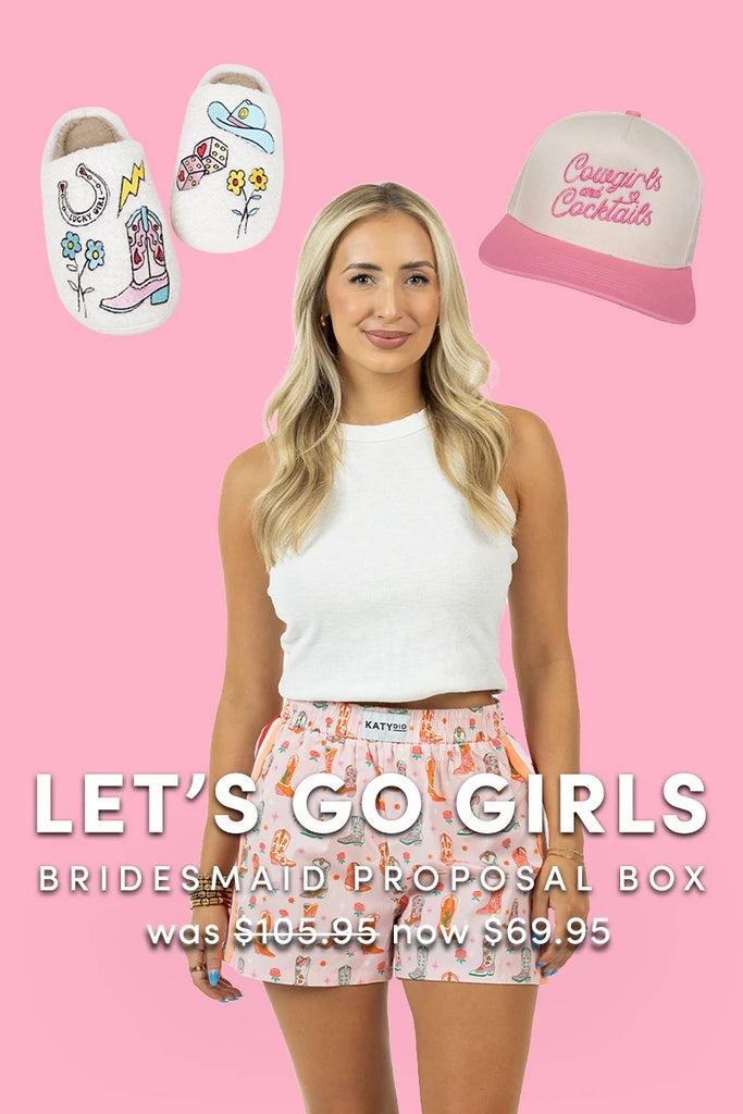 A woman in a white tank top and printed shorts stands before a pink backdrop. Above her are illustrated slippers and a pink cap. Text reads: Lets Go Girls | Bridesmaid Proposal Box by Katydid.com, was 105.95, now 69.95.