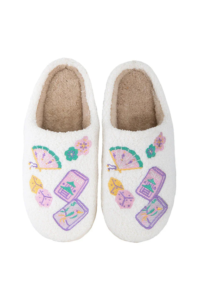 The Katydid Mahjong Pieces Cozy Slippers feature a soft, beige fuzzy lining and vibrant embroidered designs of fans, flowers, dice, and mahjong tiles for ultimate comfort and style.