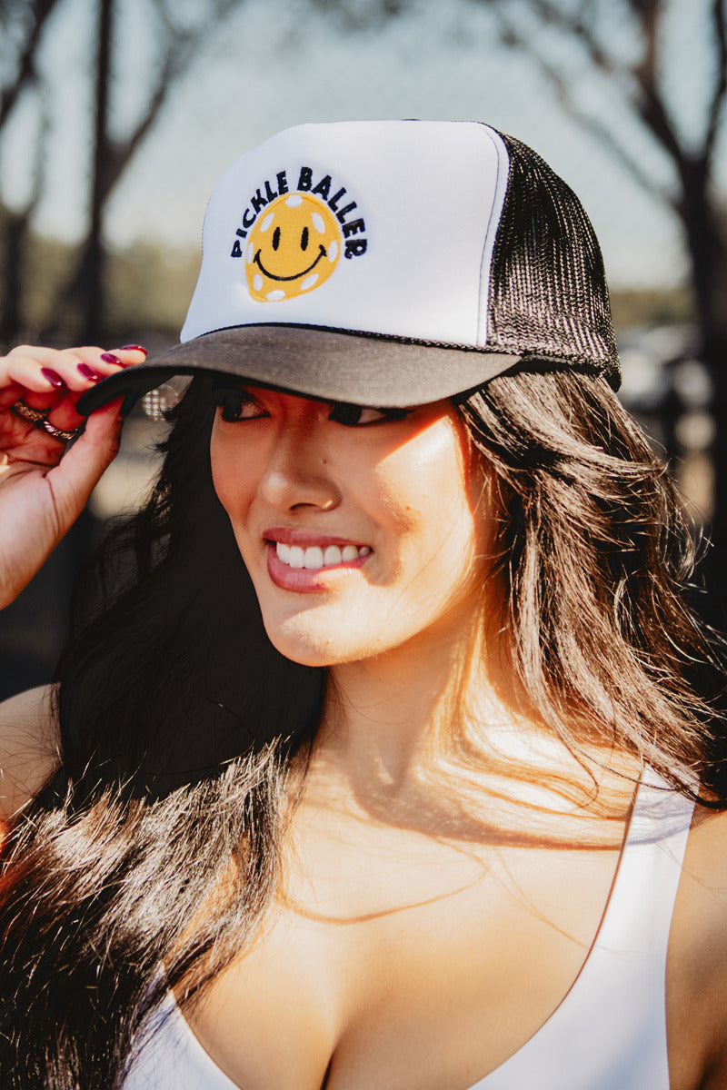 A woman wearing a black pickle baller smiley face hat