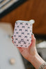 A hand holds the Katydid Black  Pink Mini Bows Wine Tumbler Cup, a reusable insulated tumbler featuring small black bows and KATYDID printed on it, standing out against a blurred background.