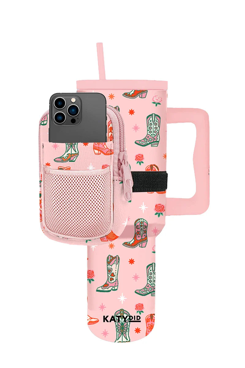 The Katydid Boots  Roses Tumbler Pouch set includes a pink travel tumbler with a handle, decorated with cowboy boots and stars, plus a matching pink zipper pouch with mesh pocket for your phone and a coordinating straw.