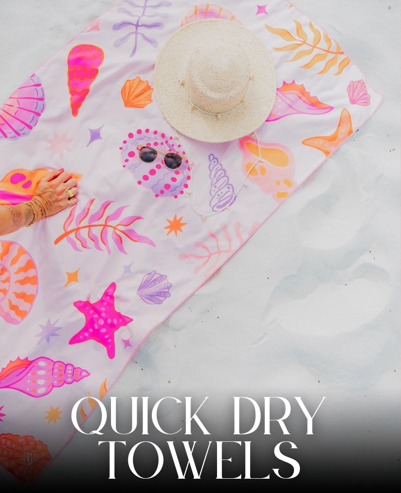 A vibrant beach towel with colorful shell patterns lies on white sand. A straw hat and sunglasses rest on the towel. Text reads, Quick Dry Towels.