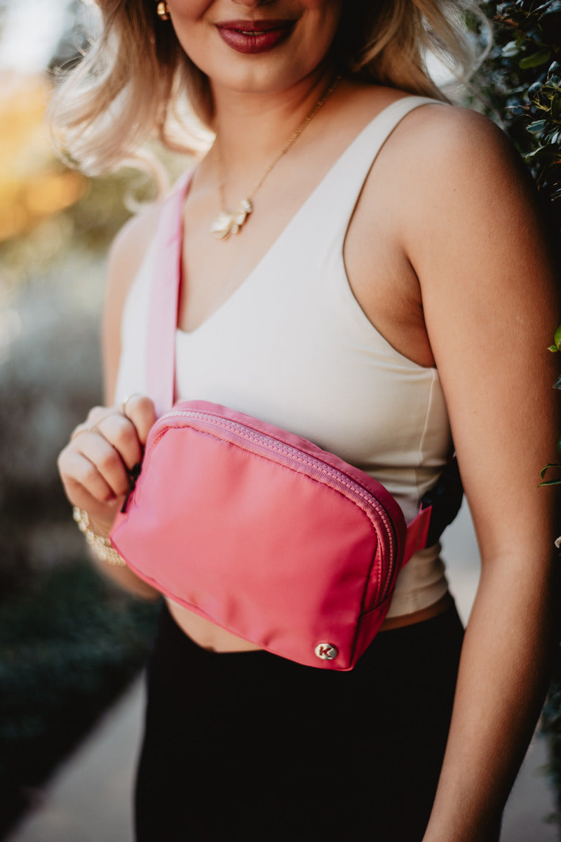A woman holding a pink belt bag in her hand