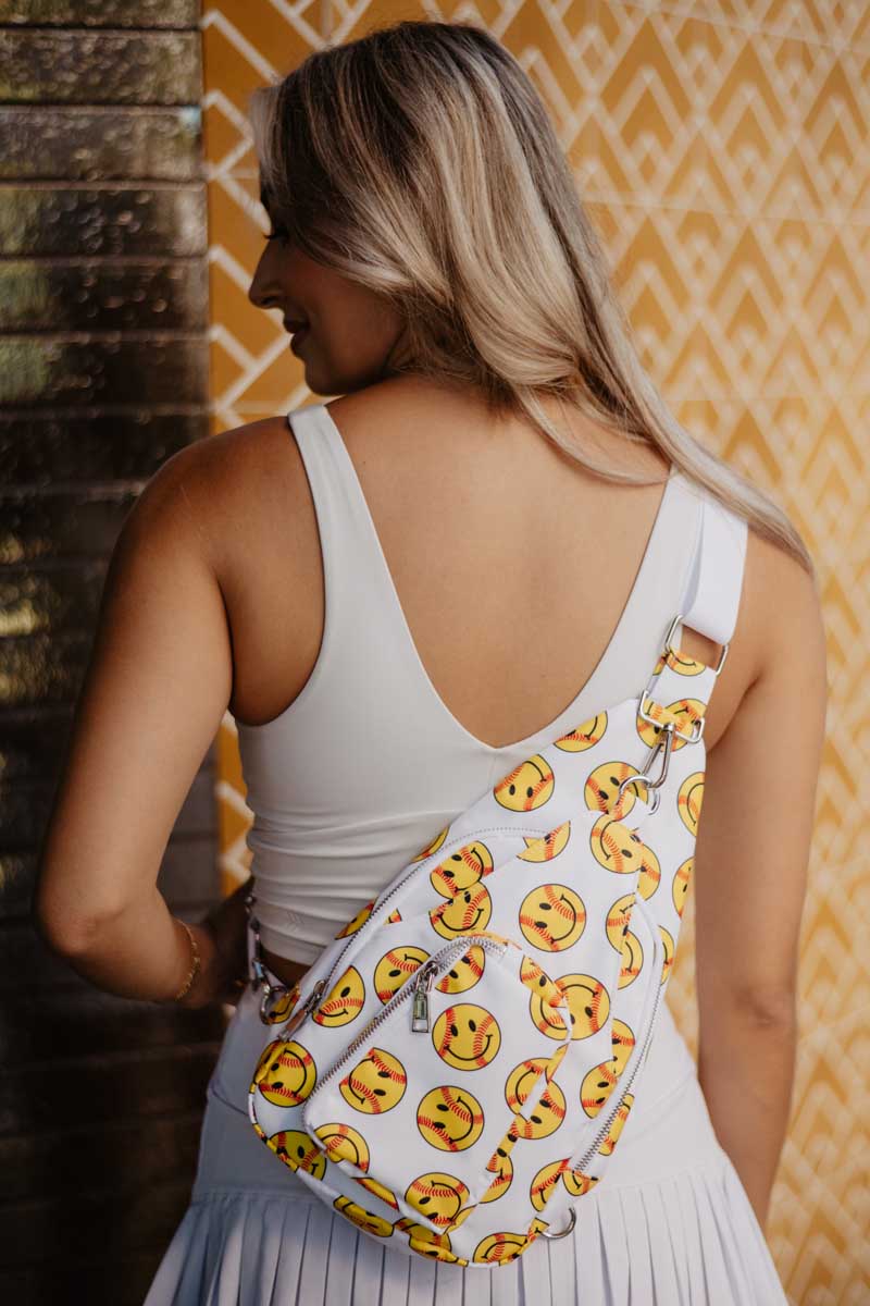A woman in a white dress with a baseball smiley face crossbody bag