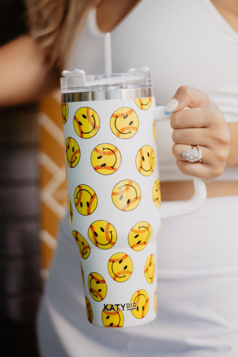 Woman holding a tumbler cup with softball smiley faces on it