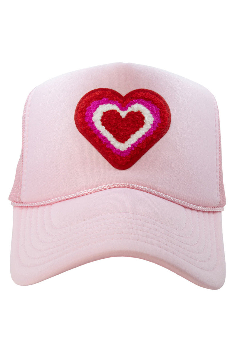 The Katydid Heart Stack Chenille Patch Womens Foam Trucker Hat features a light pink design, a bold heart patch in red, pink, and white on the front center, and an adjustable snapback closure for comfort.