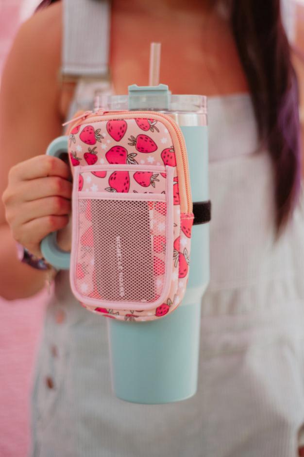 A woman holding a mint tumbler with a pink strawberry tumbler pouch