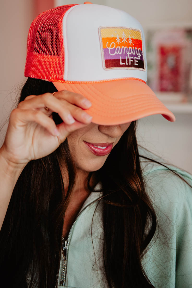 A woman wearing a trucker hat that has an embroidered Camping Life patch