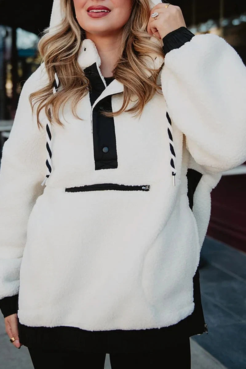 A woman enjoys the outdoors in a Katydid White Womens Two-Toned Pullover Hoodie, featuring black accents on the zipper, buttons, and hood drawstrings—a cozy and stylish layer for any day.