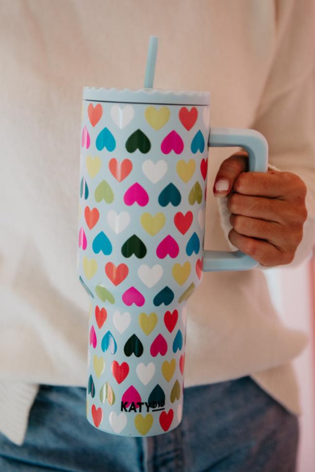 A woman holding a wine tumbler with multicolored hearts