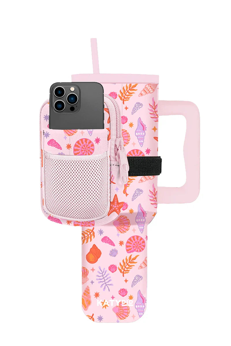 The Katydid Beach Seashells Tumbler Sling Bag pairs a pink tumbler with handle and straw, decorated with seashell and leaf designs, plus a matching neoprene pouch that fits your phone and essentials—ideal for beach days.
