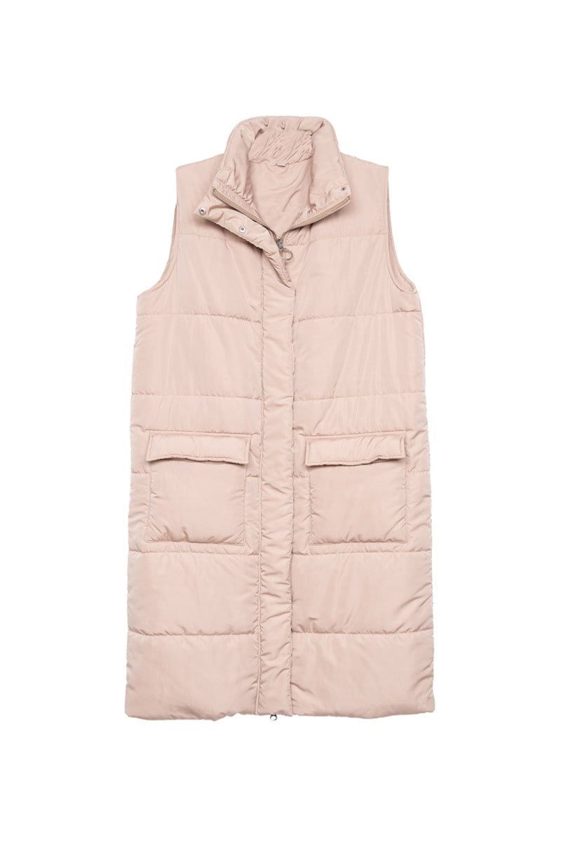 The Katydid Tan Long Quilted Puffer Vest features a sleeveless design, high collar, and two large front flap pockets. Shown laid flat on a white background, this neutral fall vest is perfect for layering.