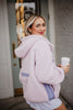 A blonde woman smiles while holding a coffee cup, wearing the Katydid Light Purple Two-Toned Sherpa Fleece Pullover as she stands outside near a door.