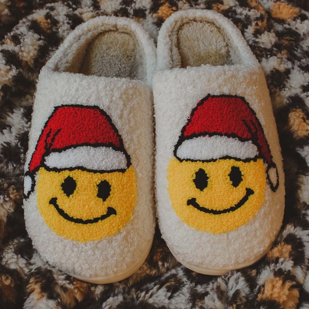 fuzzy Christmas slippers of happy face emojis wearing Santa hats